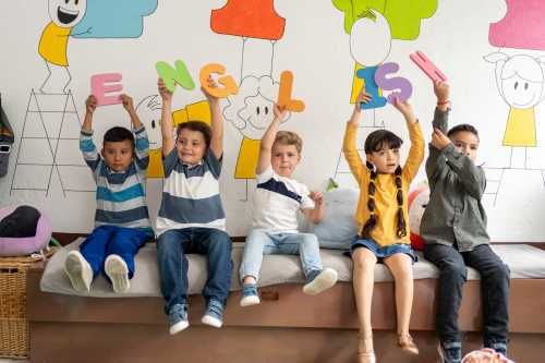 Preschool children holding large colorful letters spelling “English” in a classroom