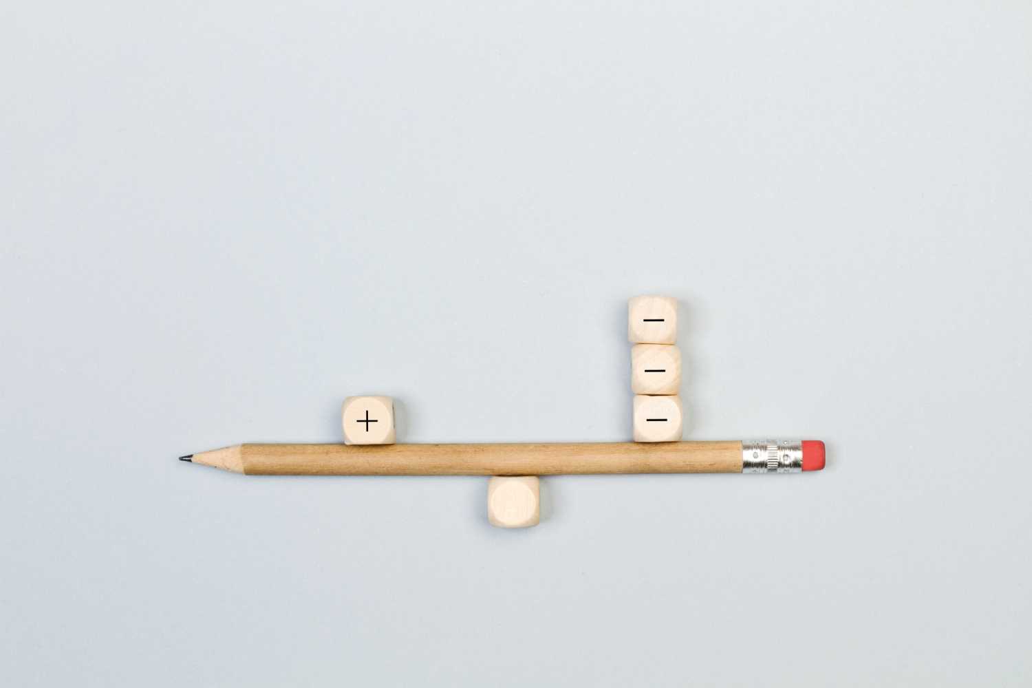 Minus and plus signs wooden cubes with a pencil in balance