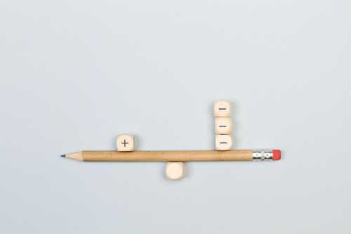 Minus and plus signs wooden cubes with a pencil in balance
