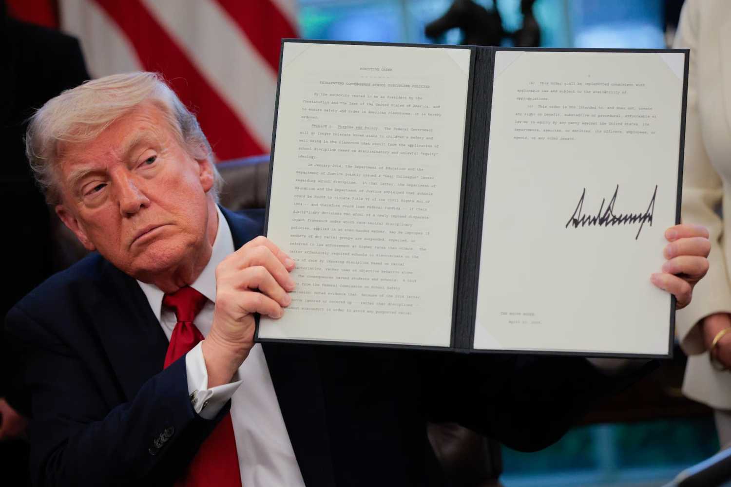 WASHINGTON, DC - APRIL 23: U.S. President Donald Trump displays a signed executive order titled "Reinstating Commonsense School Discipline Policies" in the Oval Office at the White House on April 23, 2025, in Washington, D.C.
