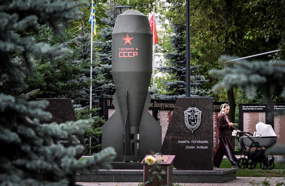 A woman rolls a baby stroller past a replica of the Soviet RDS-4 nuclear bomb installed in memory of its creators in a park in Moscow on July 29, 2026.