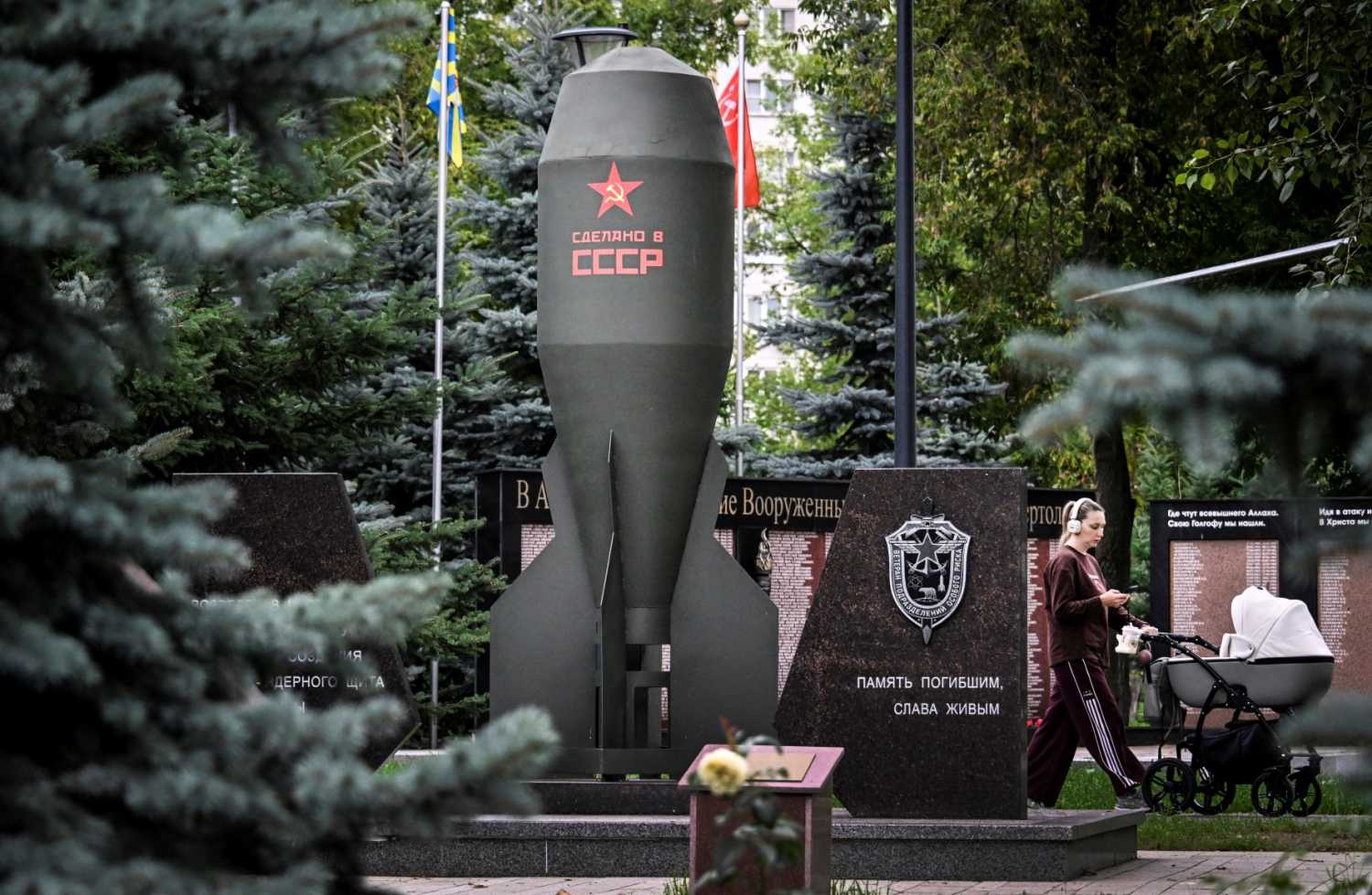 A woman rolls a baby stroller past a replica of the Soviet RDS-4 nuclear bomb installed in memory of its creators in a park in Moscow on July 29, 2026.