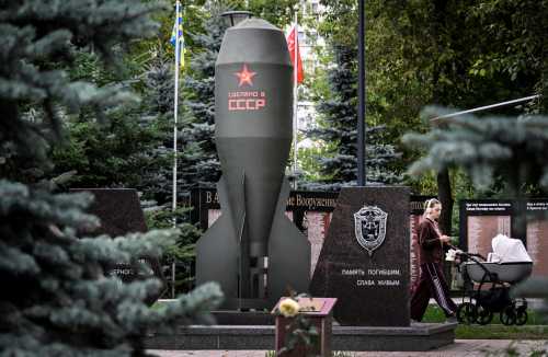 A woman rolls a baby stroller past a replica of the Soviet RDS-4 nuclear bomb installed in memory of its creators in a park in Moscow on July 29, 2026.
