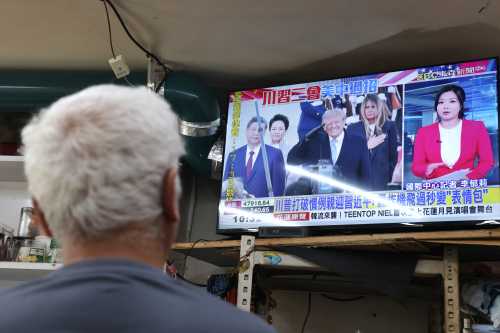 A man watches a television news report showing US President Donald Trump welcoming Chinese President Xi Jinping upon his arrival in the United States, at a restaurant in Taipei on September 24, 2026.