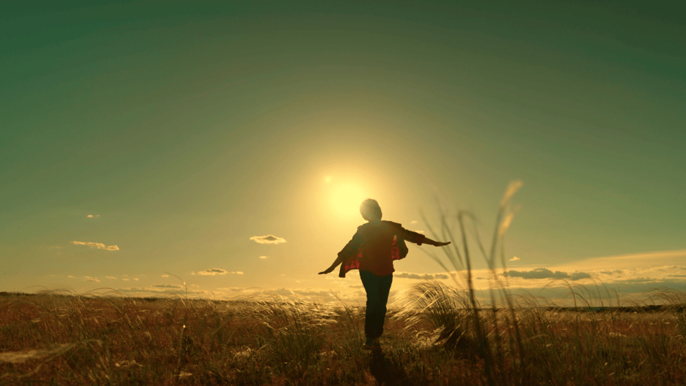 A child runs with arms outstretched at sunset.
