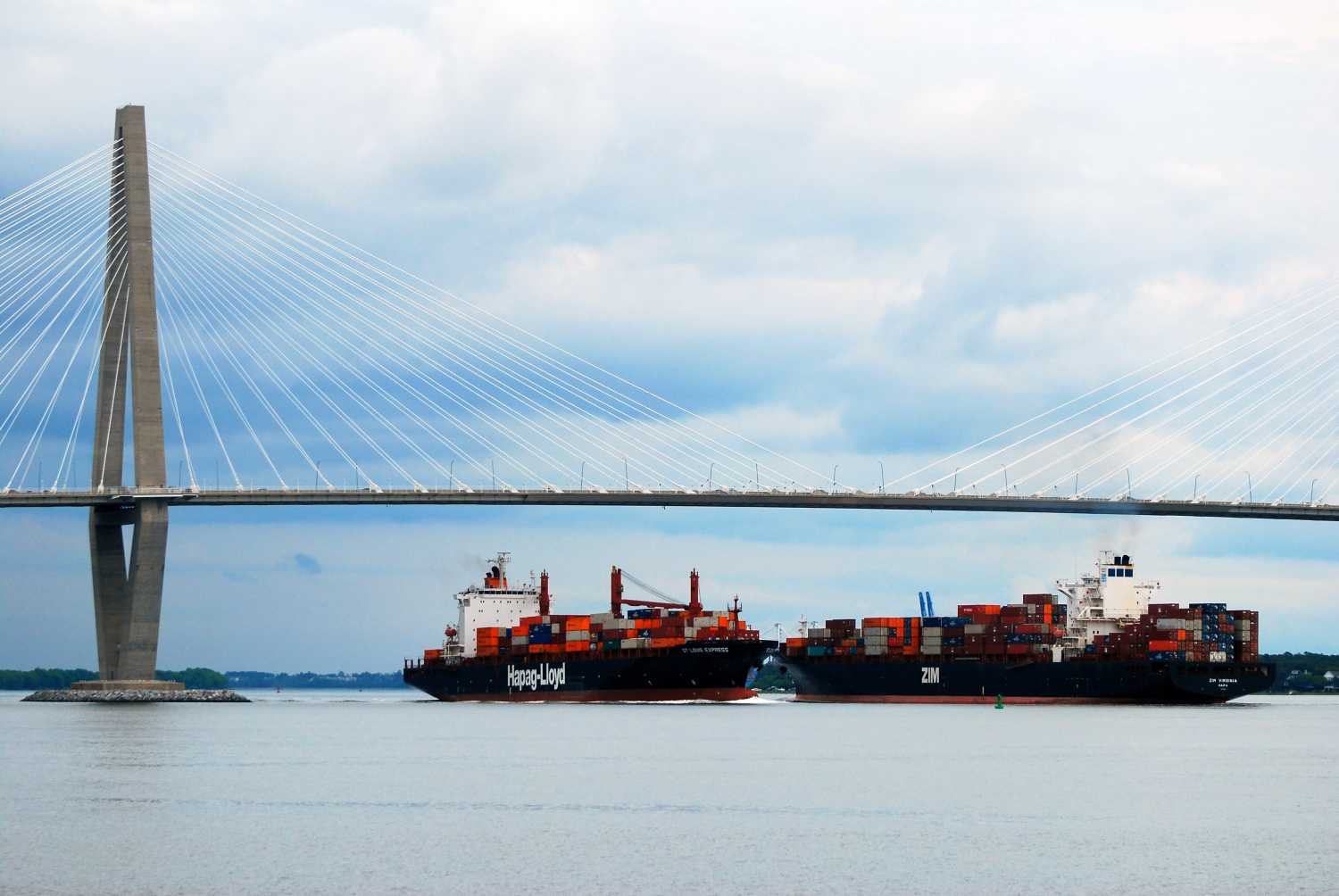 Charleston, SC, USA May 17 Two large container cargo ships, performing importing and exporting, pass each other under the Ravenel Bridge in Charleston, South Carolina